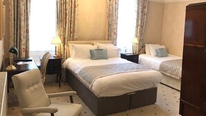 A hotel room with a large bed, two smaller beds, a chair, a desk, and a wardrobe. - Chapel House Restaurant with Rooms (Atherstone)