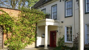 A building with a white facade, a red door, and a covered porch area. - Chapel House Restaurant with Rooms (Atherstone)
