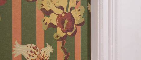 A corner of a room with a striped wallpaper featuring floral patterns.