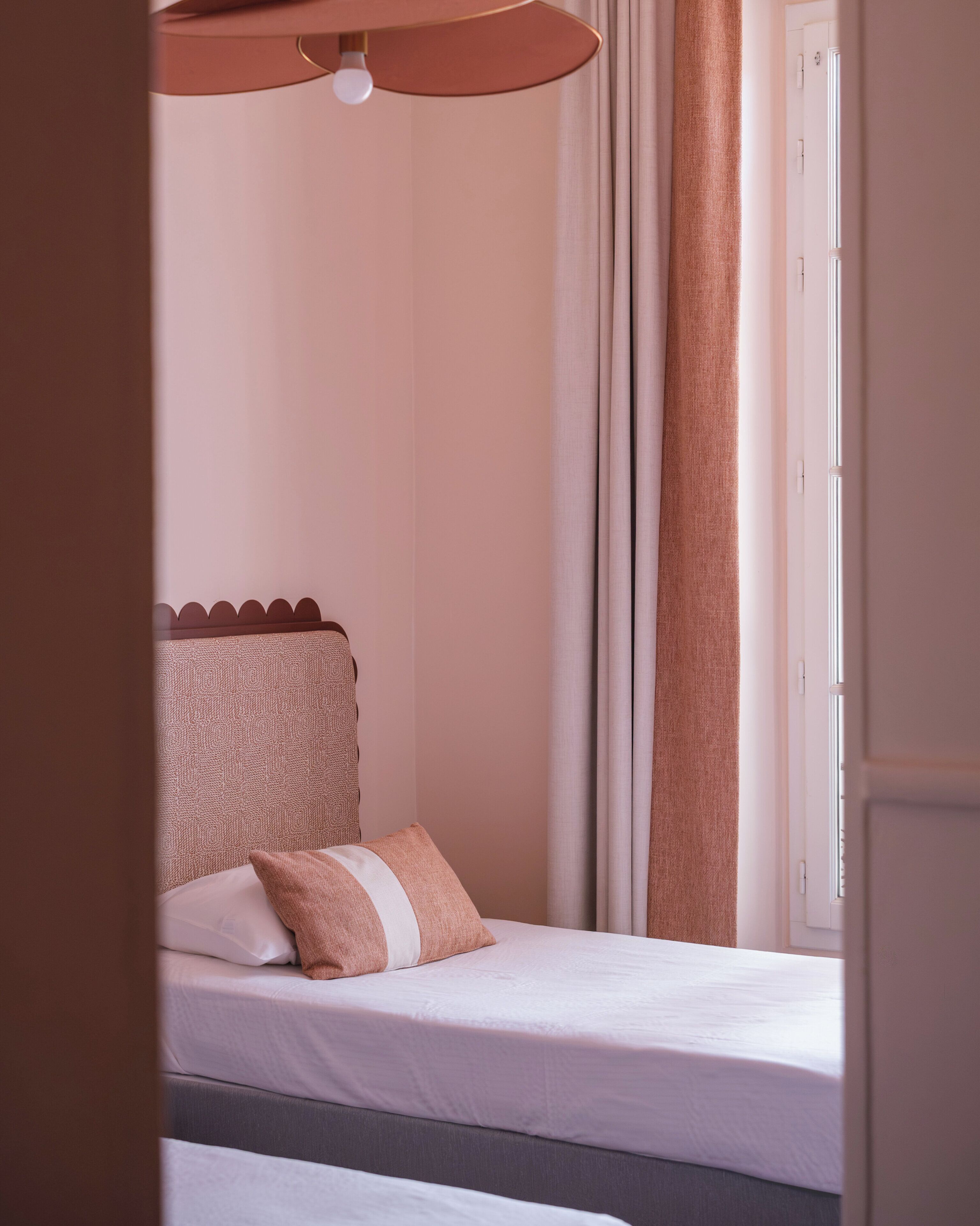A bedroom with a bed, a pillow, curtains, and a window.