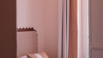 Une chambre à coucher avec un lit, un oreiller, des rideaux et une fenêtre.