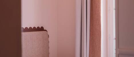 A bedroom with a bed, a pillow, curtains, and a window.