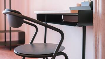 A modern chair with a curved backrest and a flat seat, positioned next to a desk with a wooden top and a black metal frame.