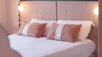 A bed with a textured headboard, two pillows, and a bedside table with a lamp.