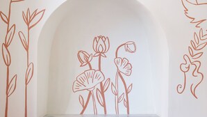 Un interno minimalista con una nicchia ad arco bianca e semplici disegni di piante.