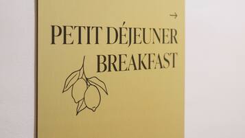 A wall-mounted sign for 'PETIT DÉJEUNER BREAKFAST' with a phone number and directional arrows.
