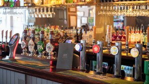 A bar with multiple beer taps, glasses, and bottles. - The Cedars Inn by Greene King Inns (Barnstaple)