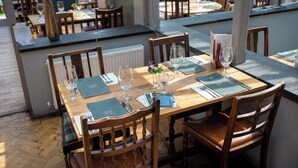 A restaurant with wooden tables and chairs, menus, and wine glasses set up for dining. - The Cedars Inn by Greene King Inns (Barnstaple)