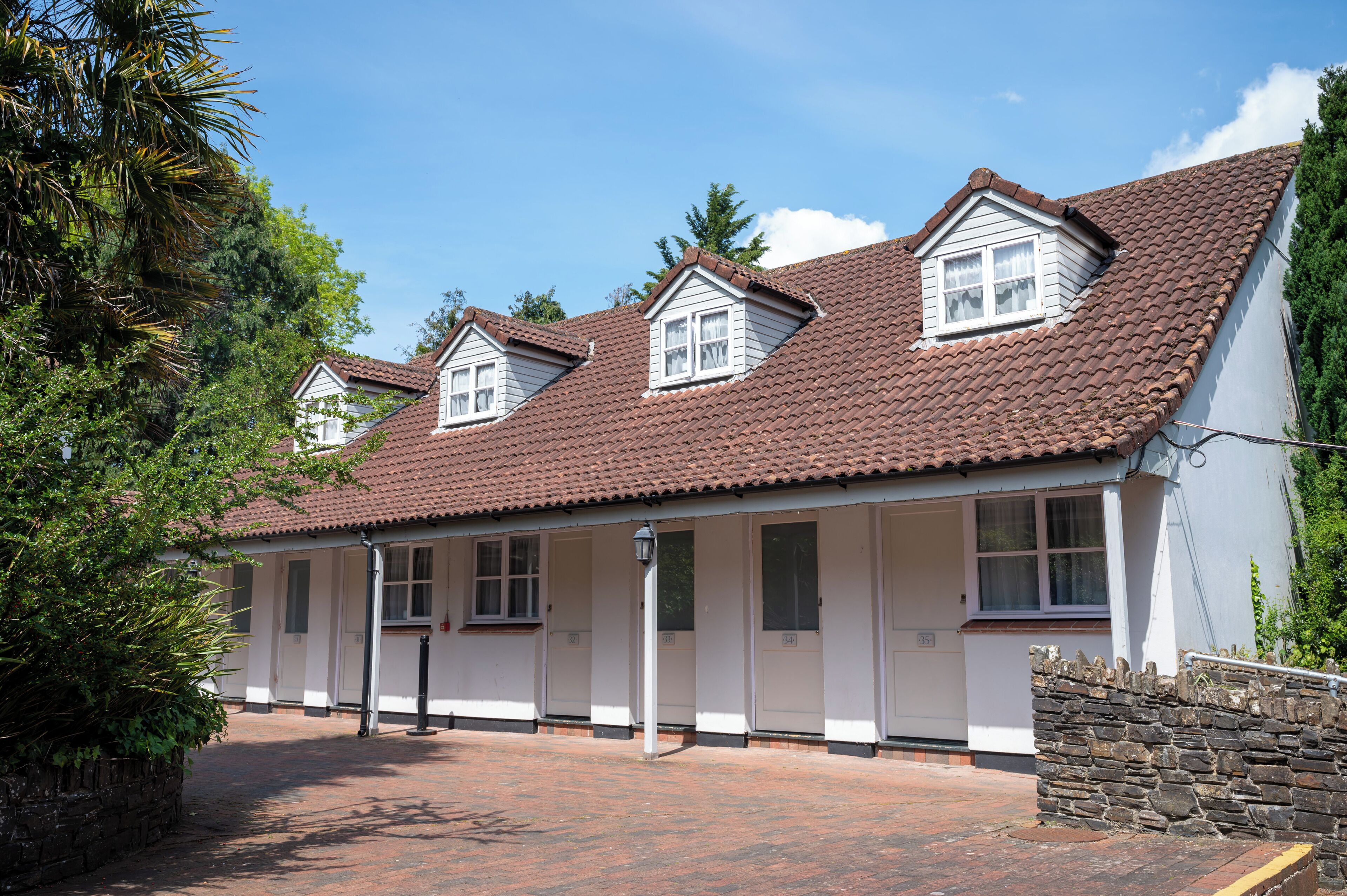 A row of white buildings with brown tiled roofs and multiple windows.