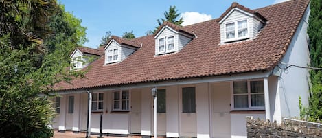 A row of white buildings with brown tiled roofs and multiple windows.
