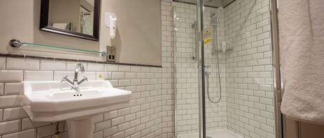 A bathroom with a white sink, a glass shower enclosure, and a mirror above the sink.
