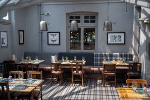 A restaurant with wooden tables and chairs, a bench, and framed pictures on the walls. - The Cedars Inn by Greene King Inns (Barnstaple)