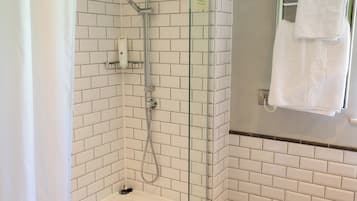 Un baño moderno con ducha envuelta en vidrio, una bañera blanca y suelo de madera.