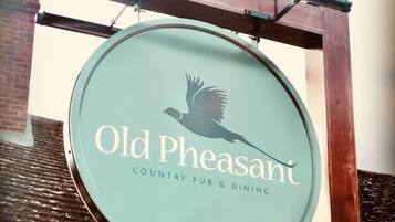 A circular sign with a bird silhouette and the text "Old Pheasant Country Pub & Dining".