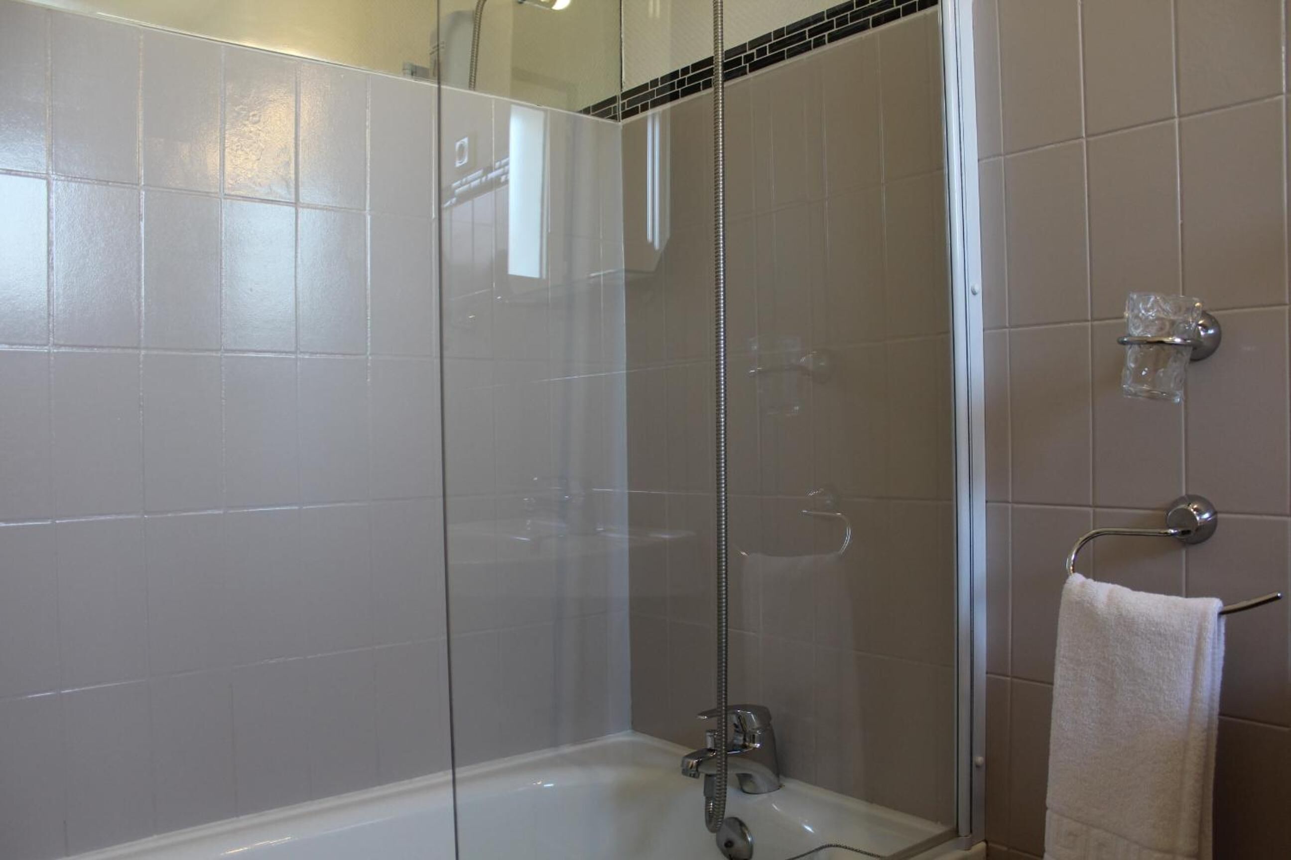 Un baño moderno con ducha de vidrio, bañera blanca y barra para toallas.
