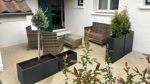 Un pequeño patio con mobiliario de mimbre y plantas en macetas.