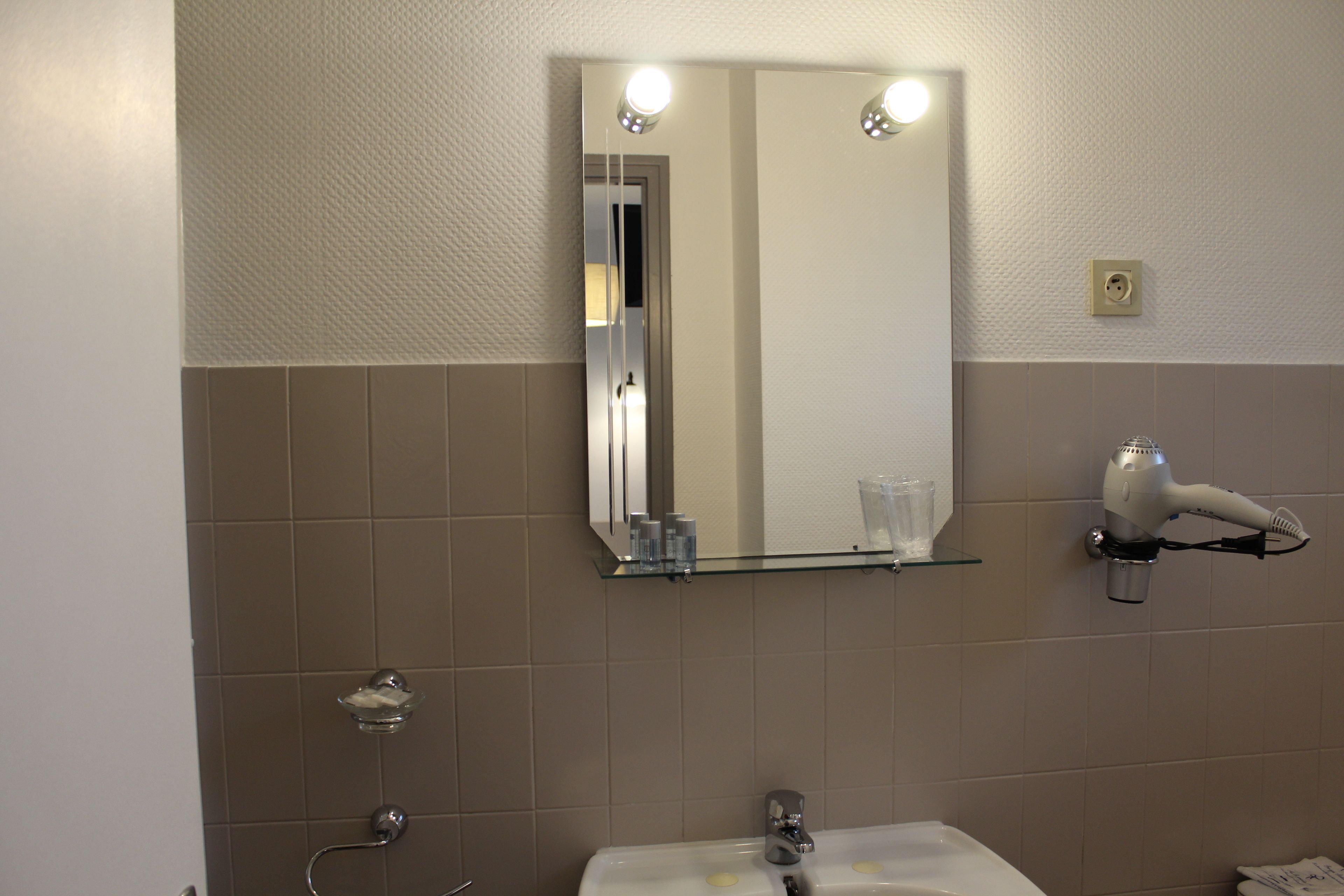 Ein Badezimmer mit Spiegel, Waschbecken und Handtuchhalter.