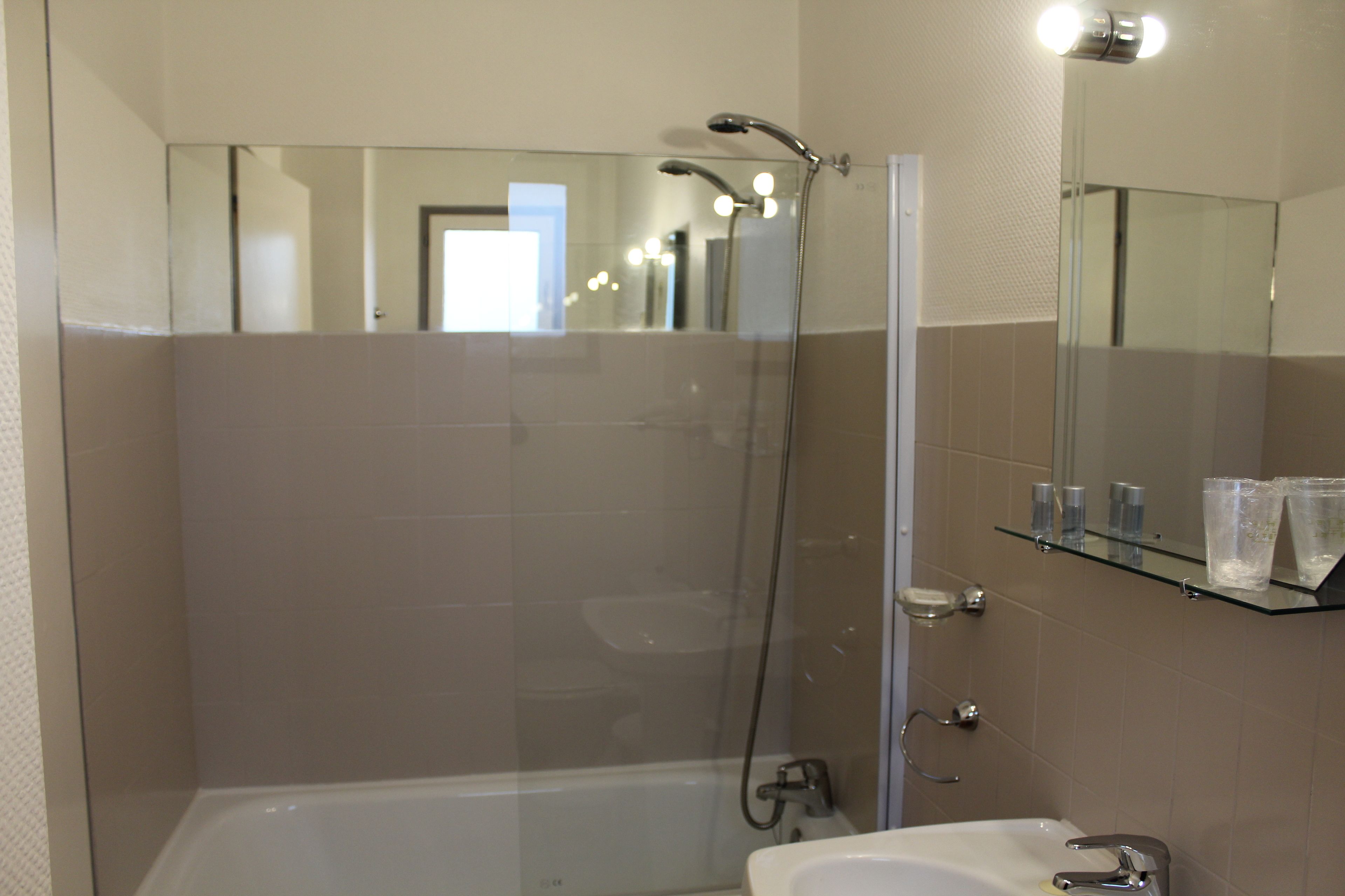 A modern bathroom with a glass-enclosed shower, a bathtub, and a sink with a mirror above.