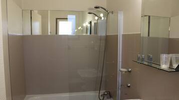 A modern bathroom with a glass-enclosed shower, a bathtub, and a sink with a mirror above.