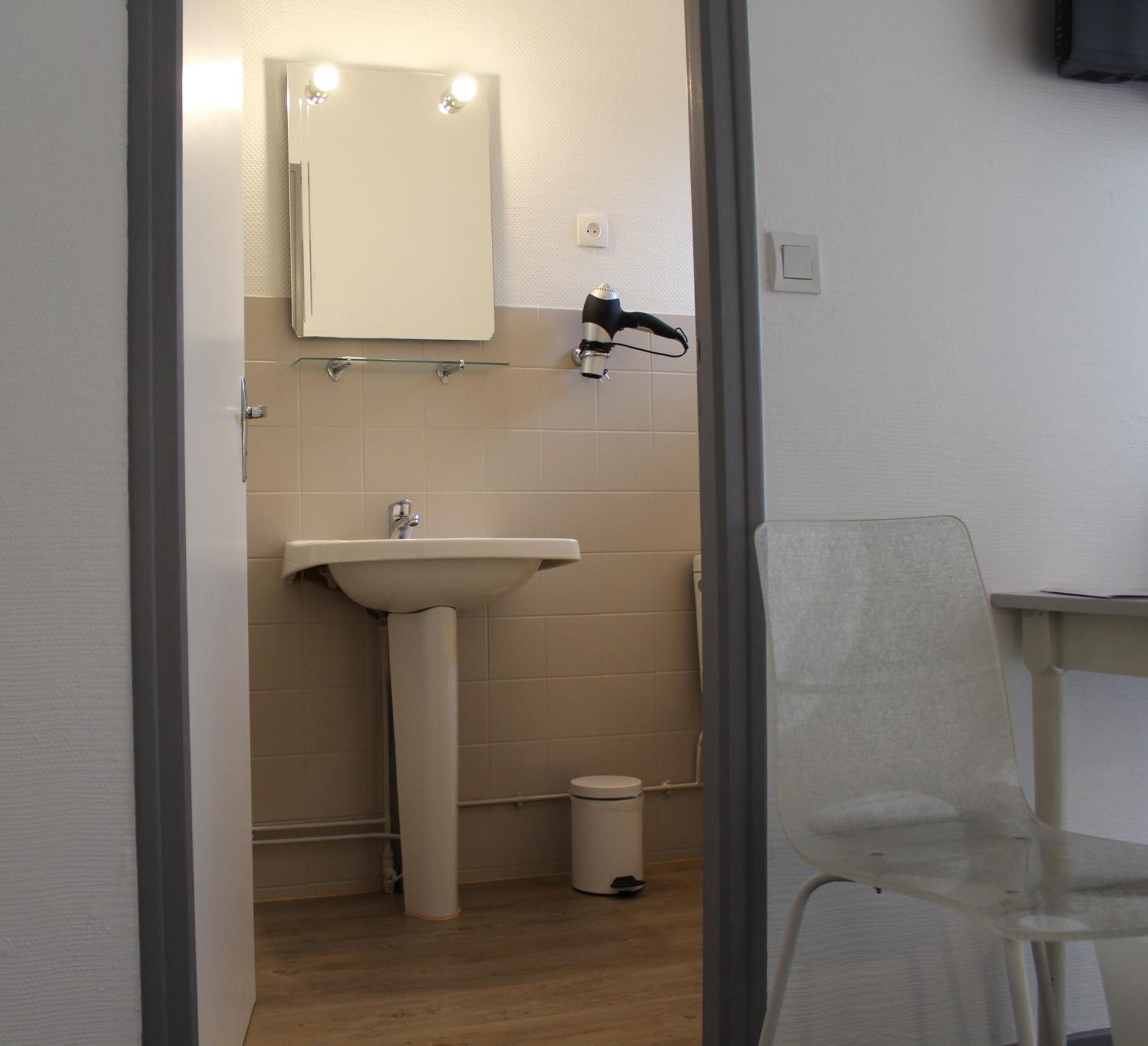 Un baño con lavamanos, espejo y secador de pelo.