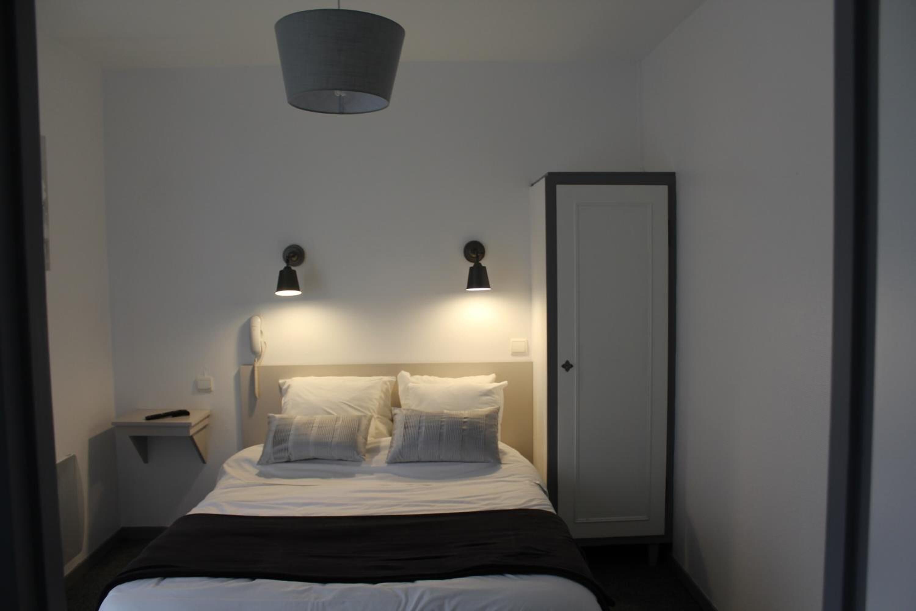 A bedroom with a bed, bedside lamps, a wardrobe, and a ceiling light.