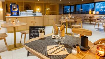 Un interior de restaurante moderno con mesas redondas, sillas de madera y una pizarra de menú.