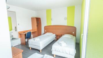 Habitación de hotel con dos camas individuales, un escritorio, una silla y un armario.