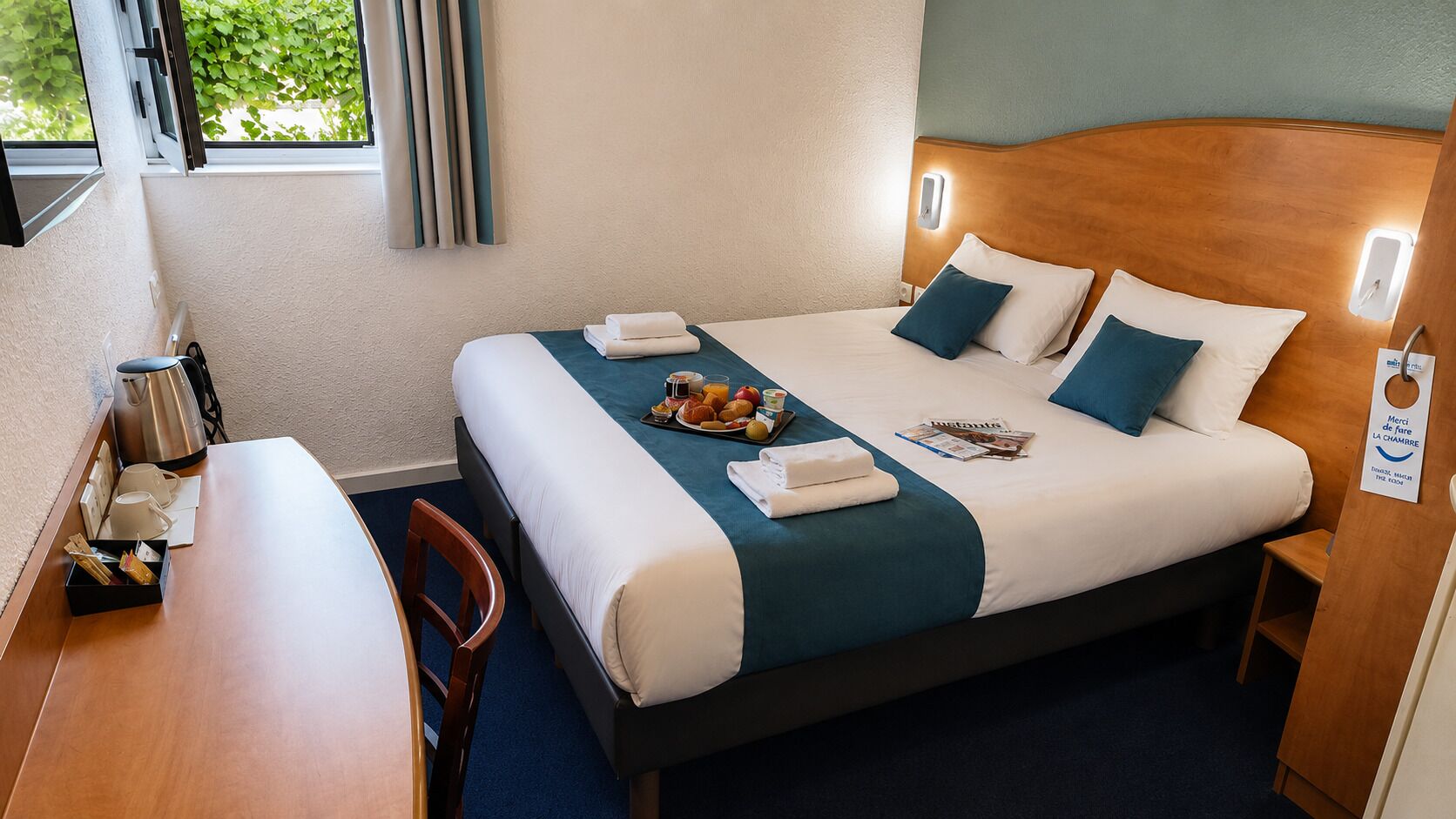 Een hotelkamer met een bed, nachtkastje en een zithoekje.