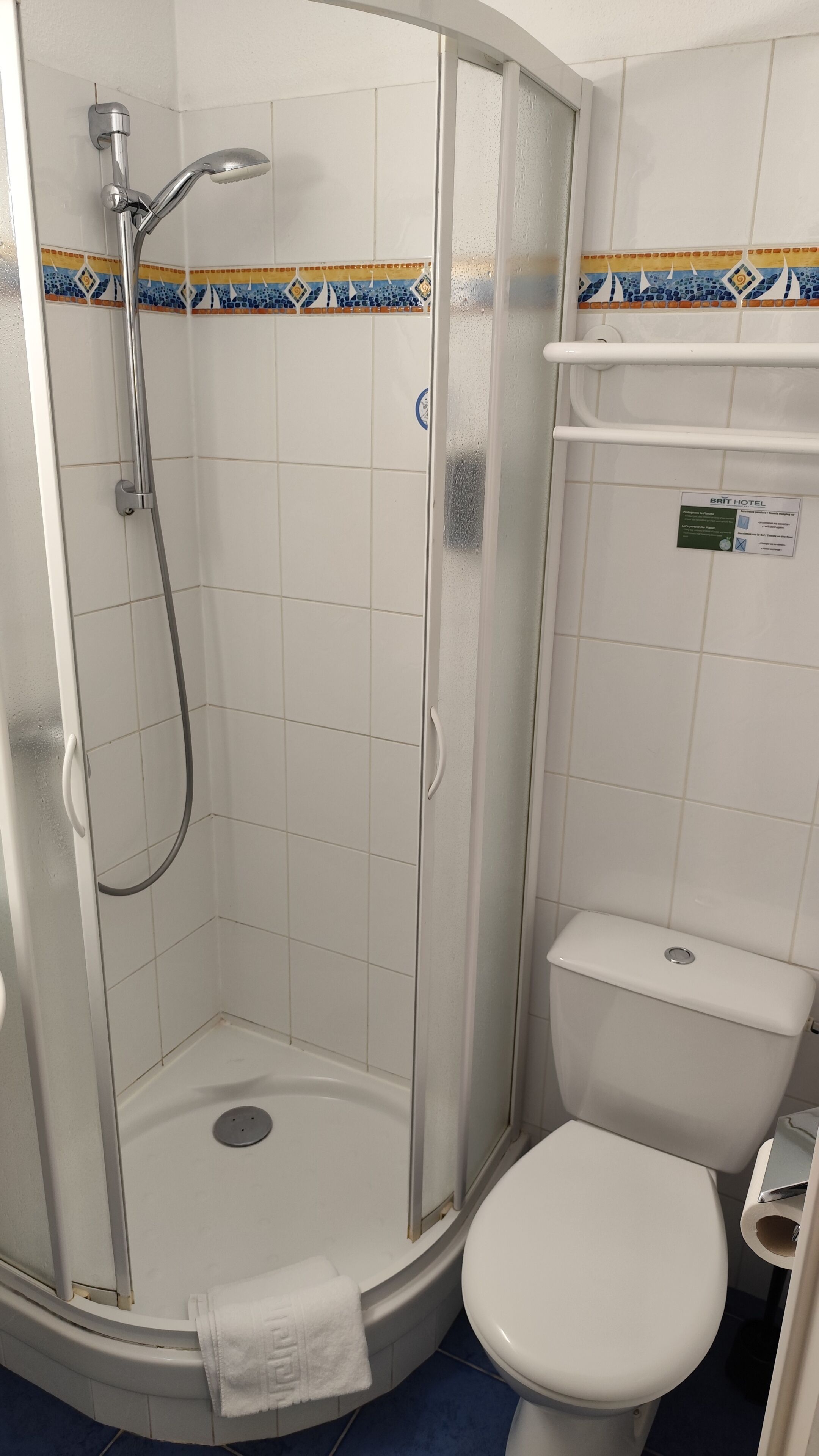 Een badkamer met een douche in een glazen cabine, een toilet en een wastafel.