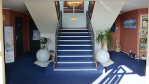 A staircase with a blue carpet leading to a landing with a ceiling light fixture. - Brit Hotel Caen Herouville (Herouville-Saint-Clair)