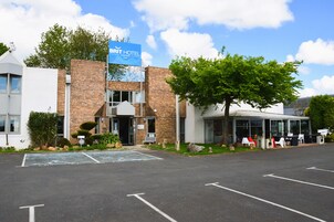 Un hotel con fachada de ladrillo moderno, un letrero y un estacionamiento.