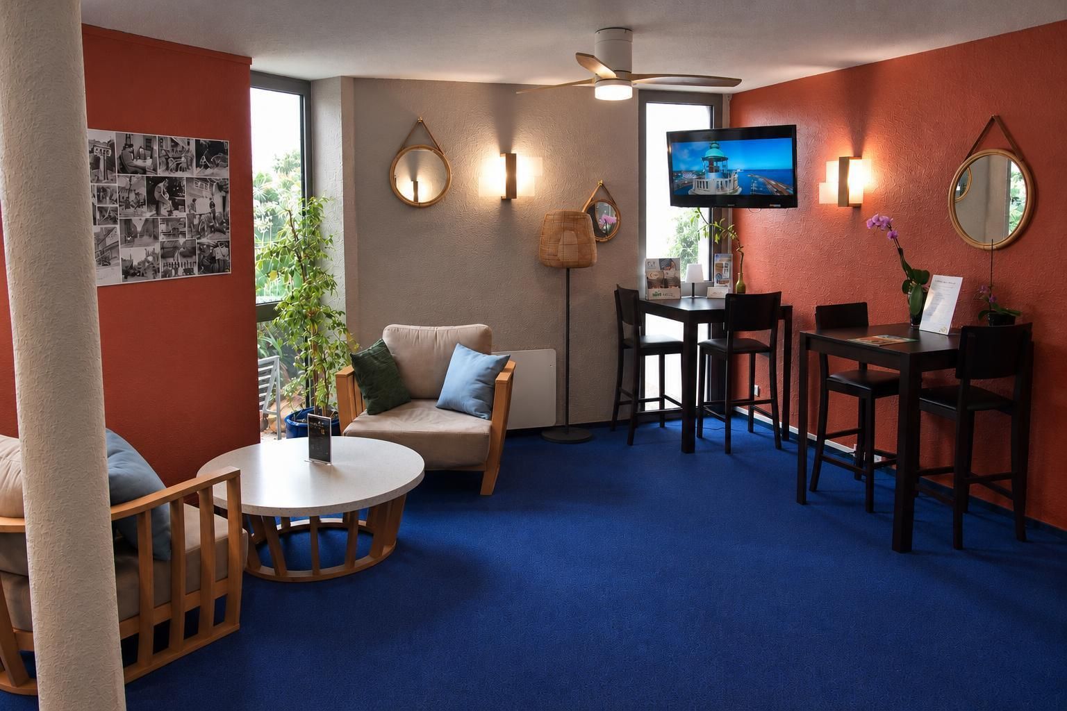 Quarto com uma mesa redonda, um sofá, uma televisão e um ventilador de teto.