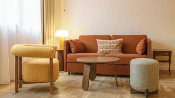 Un salon confortable avec un canapé, deux fauteuils, une table basse et une lampe.