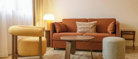 A cozy living room with a sofa, two armchairs, a coffee table, and a lamp.