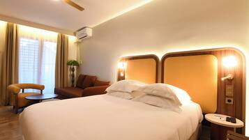 A hotel room with a large bed, a small table, a chair, and a nightstand.