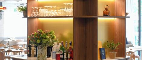 A bar area with shelves of bottles, glasses, and a small refrigerator.