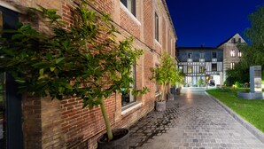 Un bâtiment en briques avec un chemin pavé menant à une entrée fermée par un portail.
