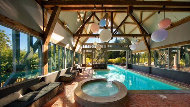 Un espace piscine doté d’un jacuzzi, de sièges et de grandes fenêtres.