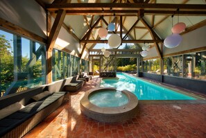 Un espace piscine doté d’un jacuzzi, de sièges et de grandes fenêtres.