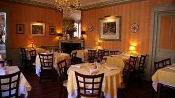 A dining area with round tables covered in yellow tablecloths, wooden chairs, and a chandelier.