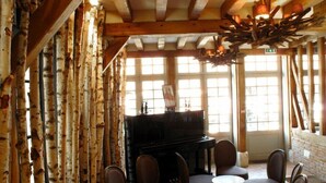 Un intérieur rustique avec des murs recouverts d’écorce de bouleau, un piano et des meubles en bois.