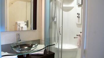 A modern bathroom with a glass bowl sink, a glass-enclosed shower, and a white toilet.