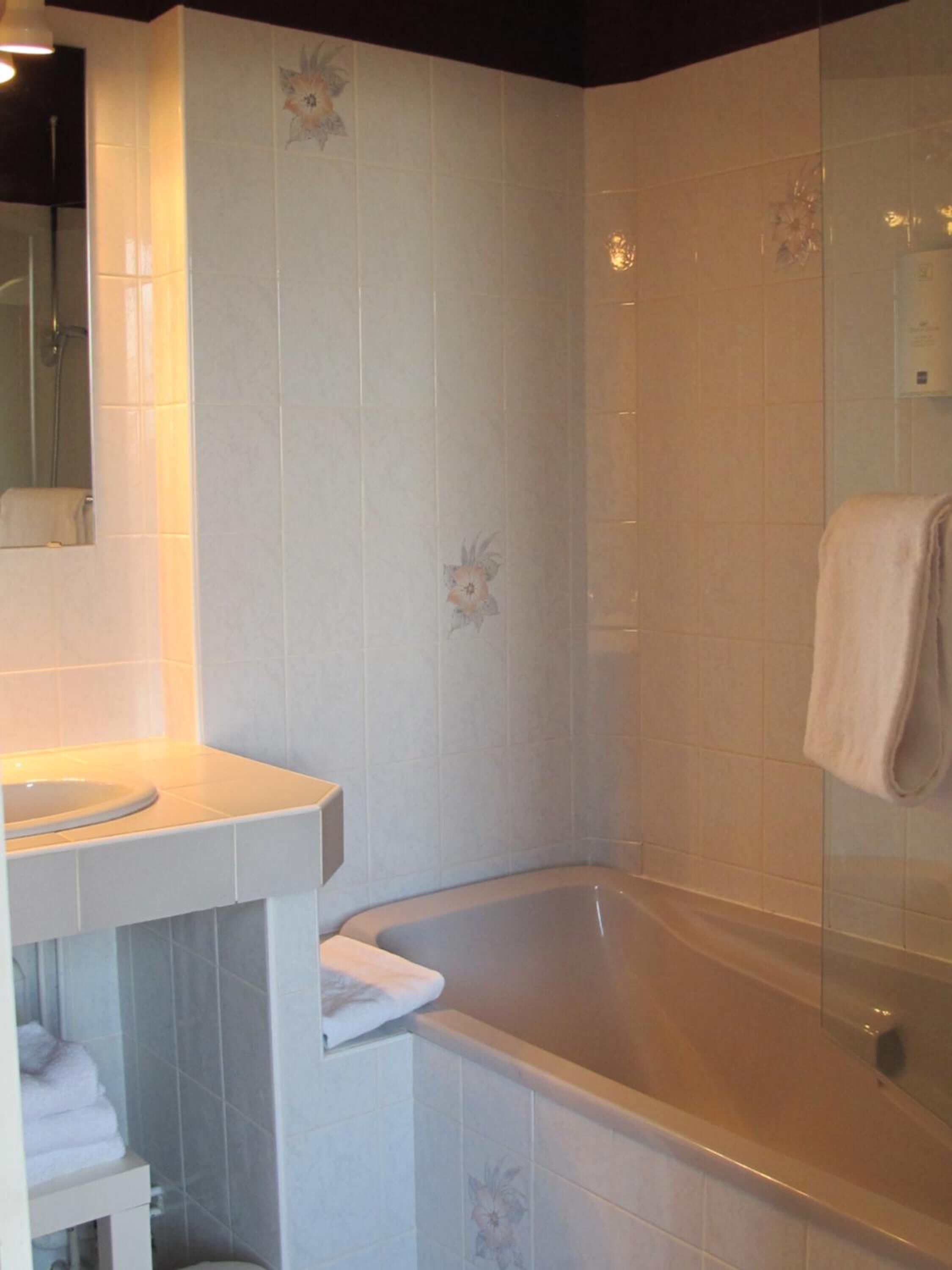 A bathroom with a bathtub, a sink, and a mirror.