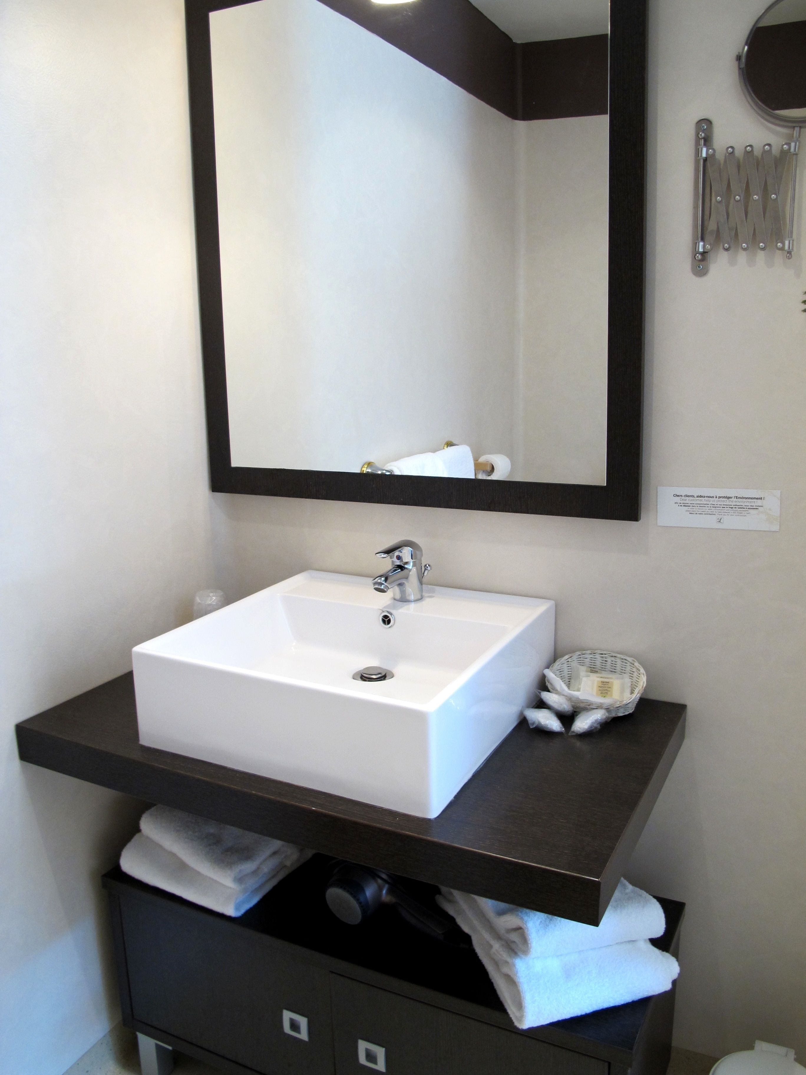 A bathroom with a white sink, dark countertop, and a mirror above.