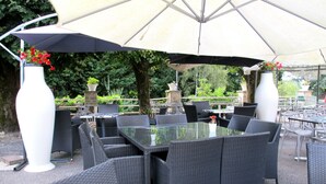 An outdoor seating area with wicker furniture and large umbrellas. - Deshors Foujanet (Chamboulive)