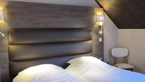 A modern bedroom with a large bed, a headboard with built-in lighting, and a small bedside table. - Deshors Foujanet (Chamboulive)