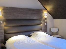 Quarto moderno com uma cama grande, cabeceira com iluminação embutida e uma pequena mesa de cabeceira.