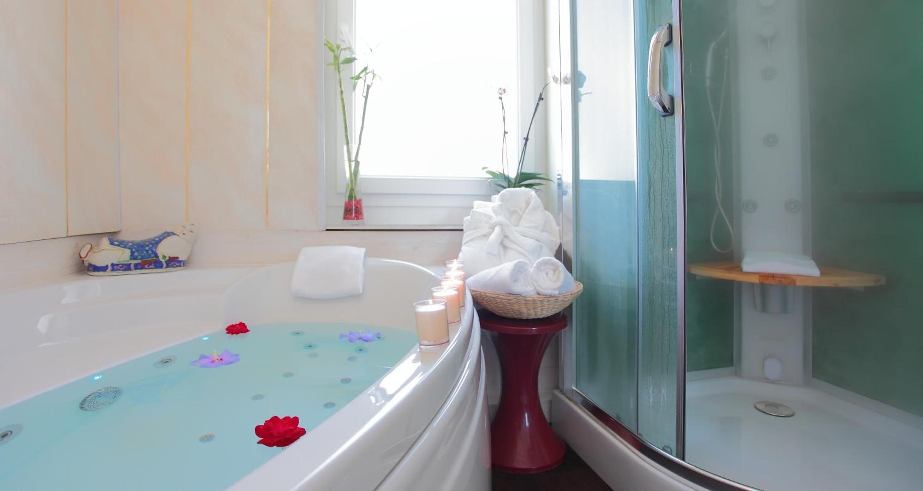 Un baño con bañera, ducha y zona de ducha con cerramiento de vidrio. Hay toallas y una cesta al lado de la bañera.