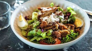 A bowl of salad with lettuce, tomatoes, and a hard-boiled egg.