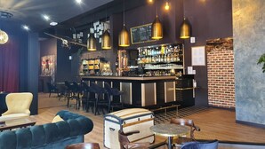 Een bar met een toonbank, zitplaatsen en hangende lampen.
